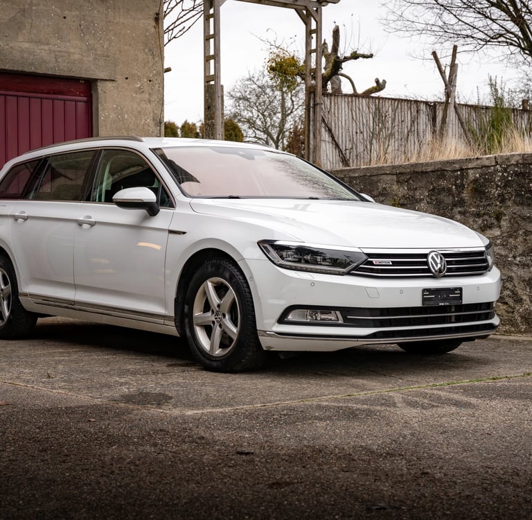 a white volkswagen passat parked in front of a red door