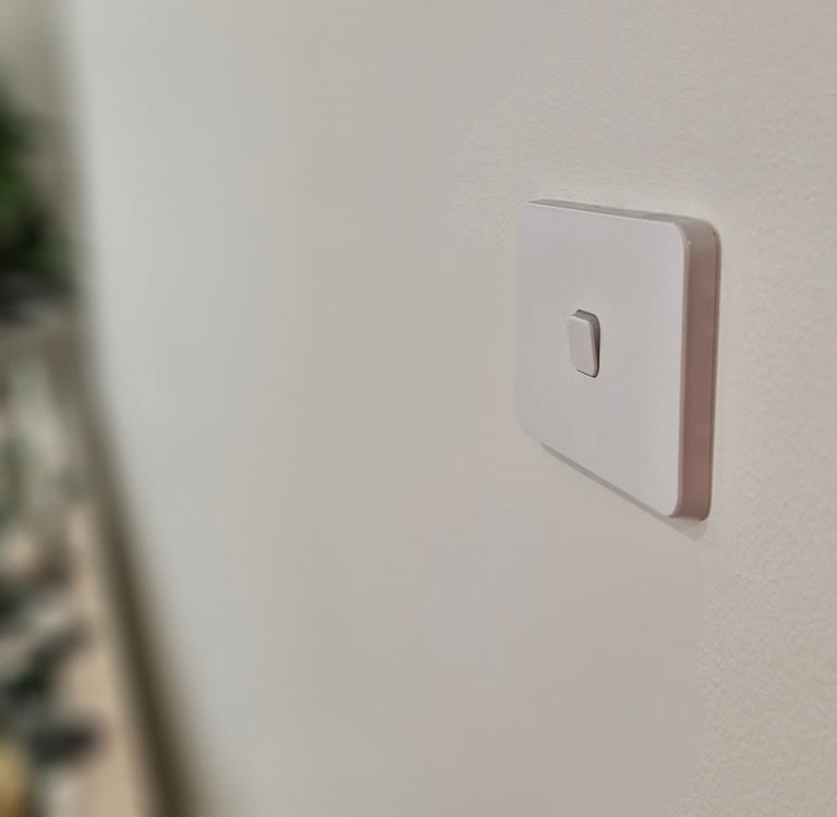 A white light switch on a white wall
