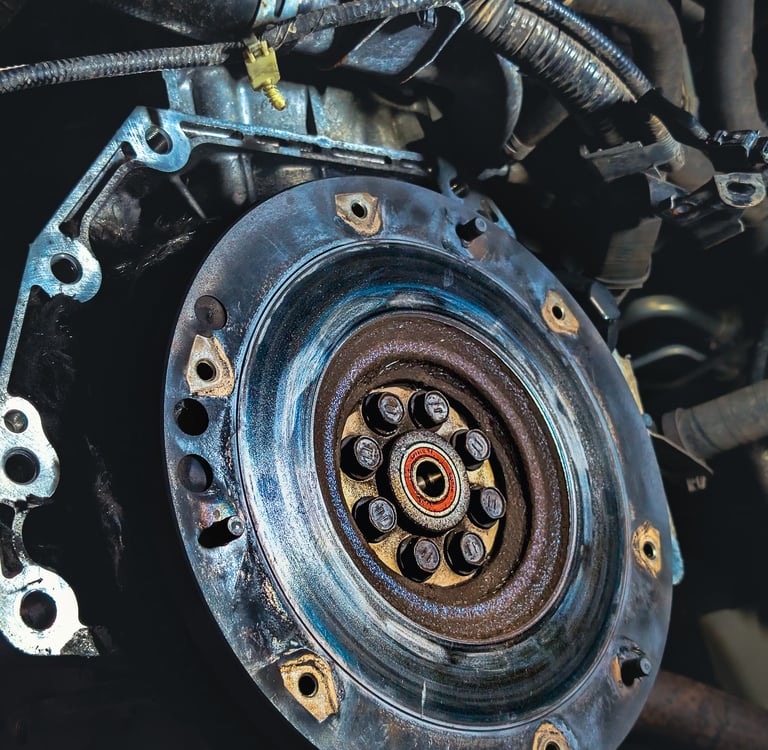 Close-up of a car flywheel and pilot bearing installed on an engine crankshaft during a clutch repair.