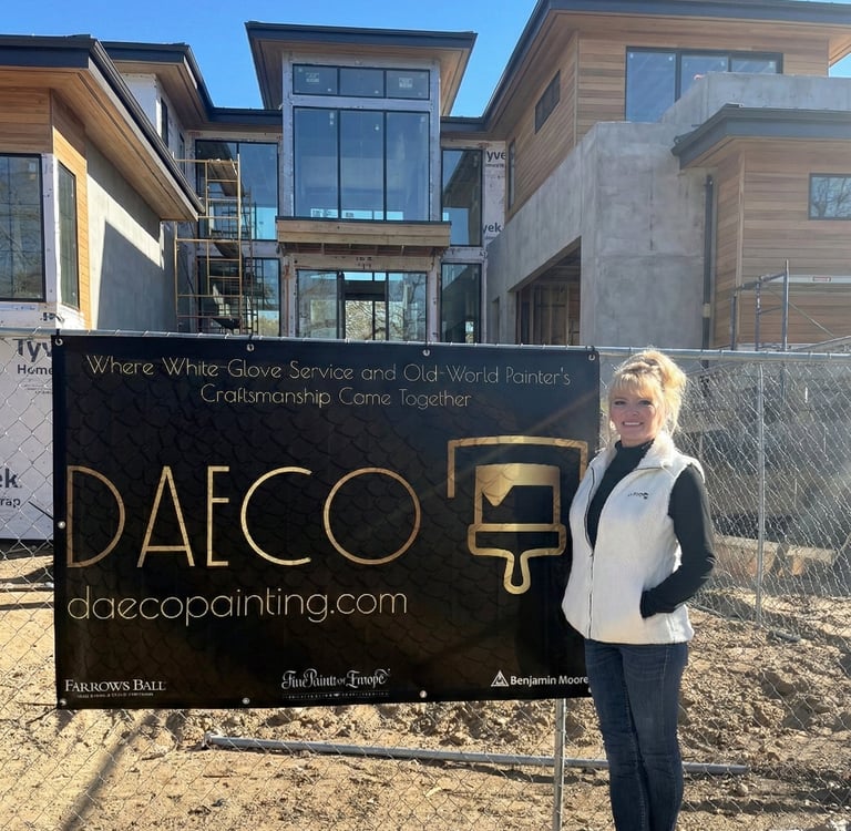 Daeco Painting representative standing at a luxury new construction site next to a company banner re