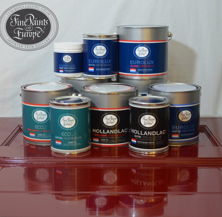 Assorted cans of Fine Paints of Europe Hollandlac and Eurolux paints displayed on a high-gloss red surface.