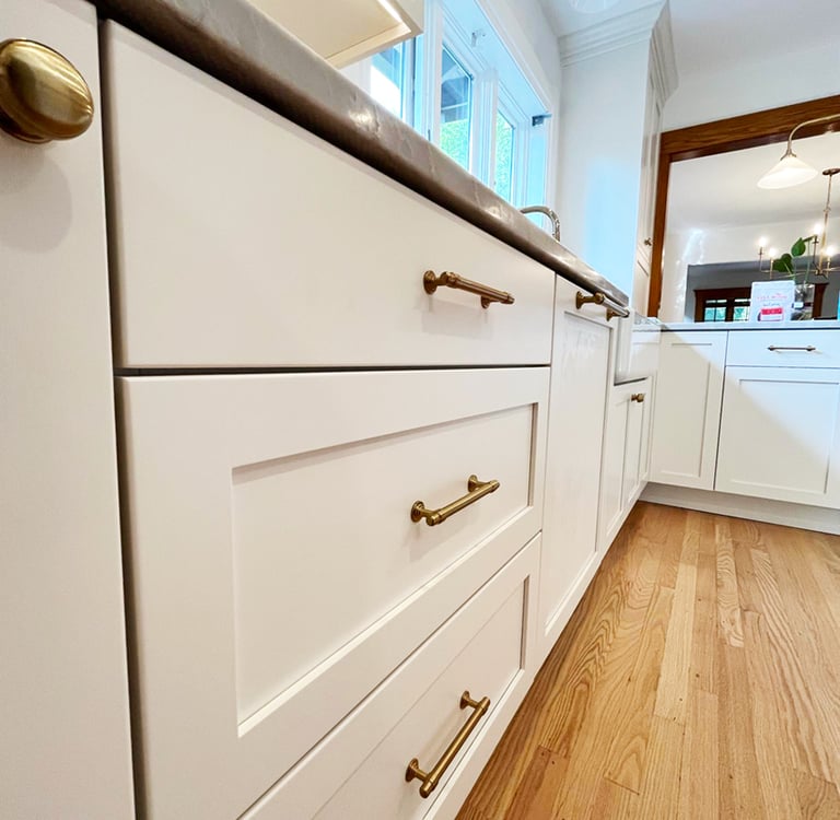 a kitchen with white cabinets and a wooden floor