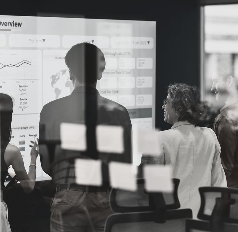 a group standing in front of a white board discussing a slide titled Data Analytics Overview
