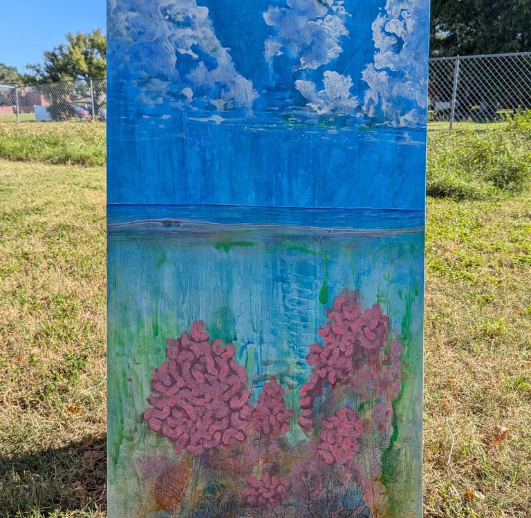 A color dense painting of a coral reef with a clouded blue sky above rendered in gloss acrylics on linen by Kathy LaFollett.