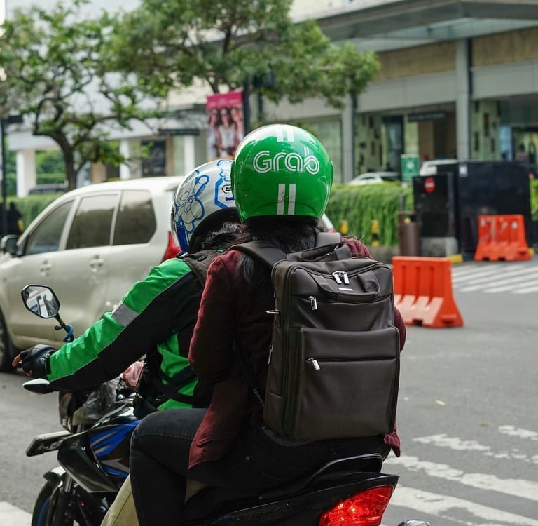 A Grab motorbike rider carrying a passenger on a city street in Vietnam