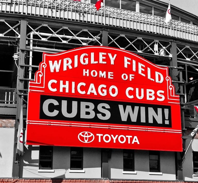 a large red and white sign that says cubs win at wrigley field
