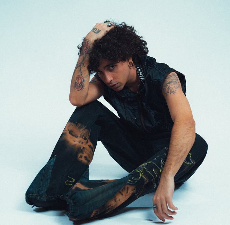 Klaus Noir su sfondo bianco seduto e con una mano in testa