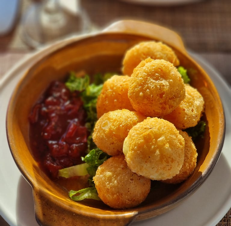 Golden fried breaded brie cheese balls served with a sweet cranberry dipping sauce and garnish.