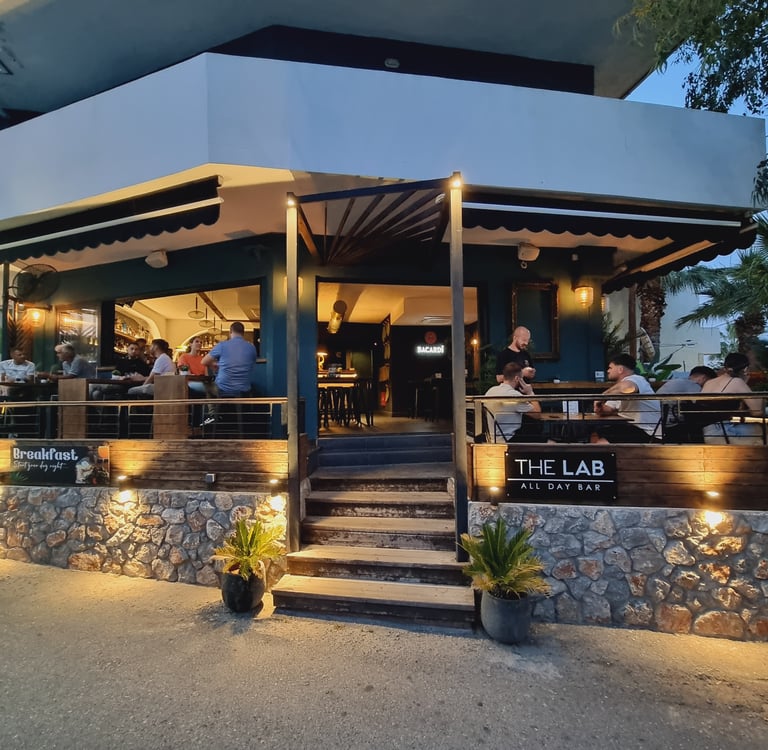 Customers dining at The Lab All Day Bar outdoor patio with stone walls and evening lighting.