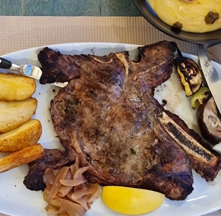 Grilled t-bone steak served with potato wedges, caramelized onions, and a side of creamy polenta.