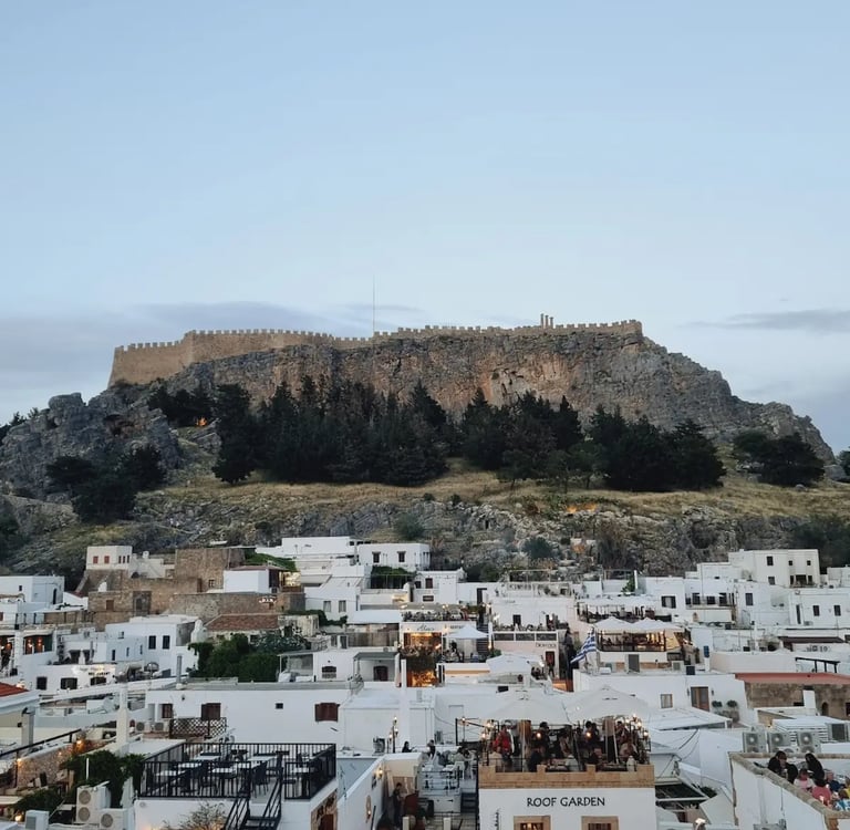 Panoramic view of the Acropolis of Lindos towering over white buildings in Rhodes, Greece.