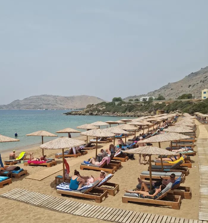 a beach with many people sitting on lounge chairs