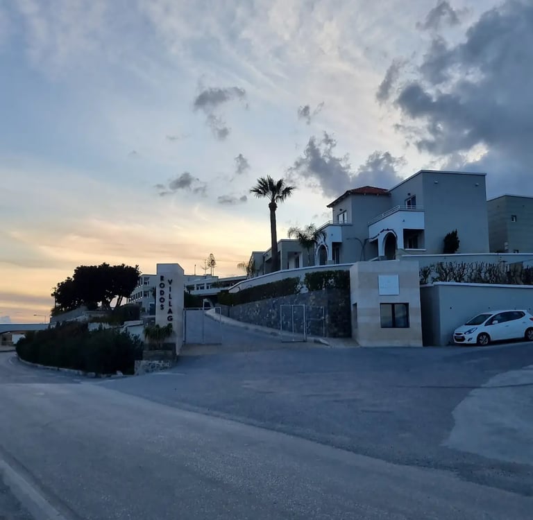 Luxury Rodos Village resort villas in Rhodes, Greece, during a scenic sunset with palm trees.