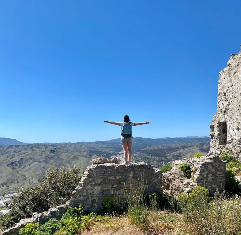 a woman standing on a rock formation with her arms outstretched out