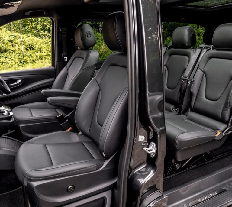 Luxury black leather seats inside a spacious Mercedes-Benz passenger van with modern interior design.