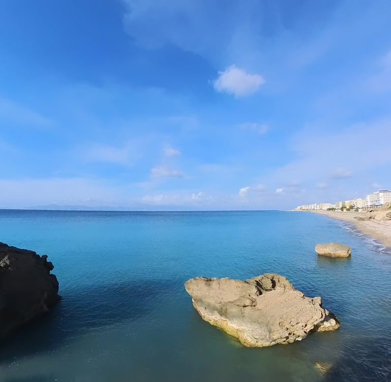 Scenic coastal view of Rhodes, Greece with turquoise Mediterranean water and rocky beach.