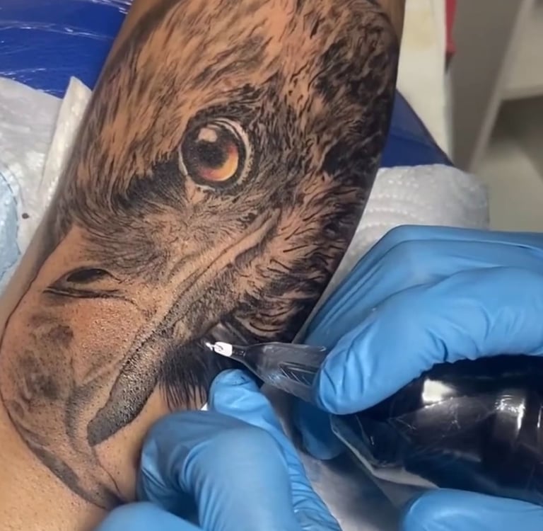 Detailed black and grey realism bald eagle tattoo being inked on a forearm by a professional artist.