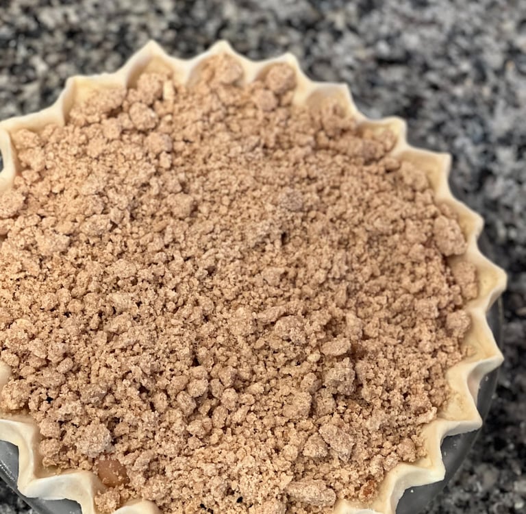 Freshly baked homemade apple crumble pie with a decorative fluted crust and buttery streusel topping.