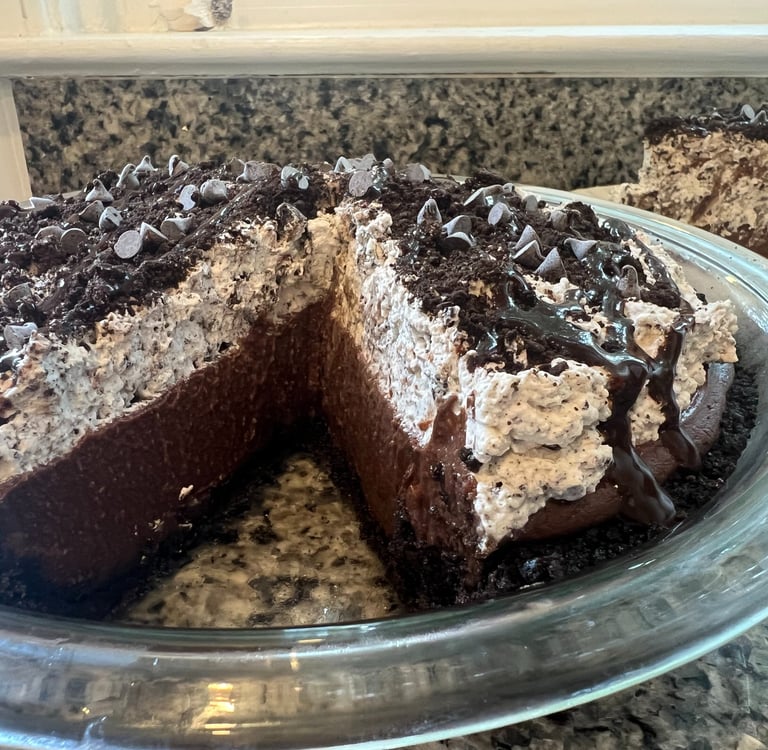 chocolate silk pie with cookies and cream whipped topping and chocolate chips in a glass dish.