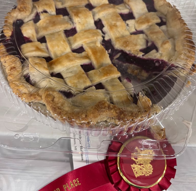 Award winning homemade blueberry pie with a golden lattice crust and a red second place ribbon.
