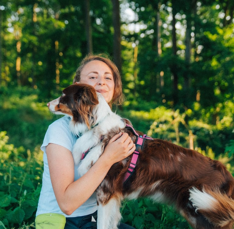 Toni hält Hund im Arm auf Baumstamm – achtsamer Moment im Waldbaden bei Takoda