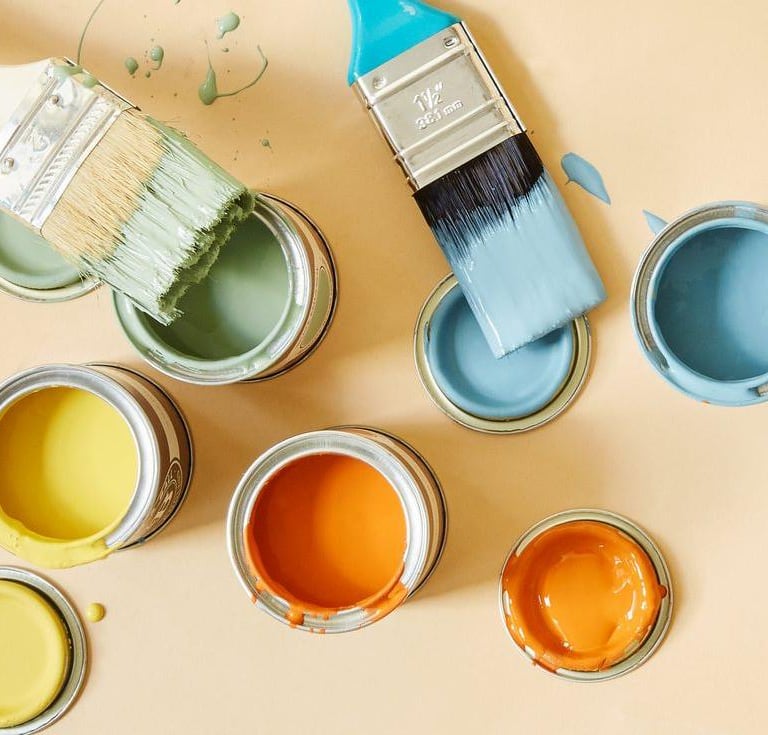 Ekologiczne farby w pastelowych kolorach. Otwarte puszki gotowe do malowania a na nich pędzle