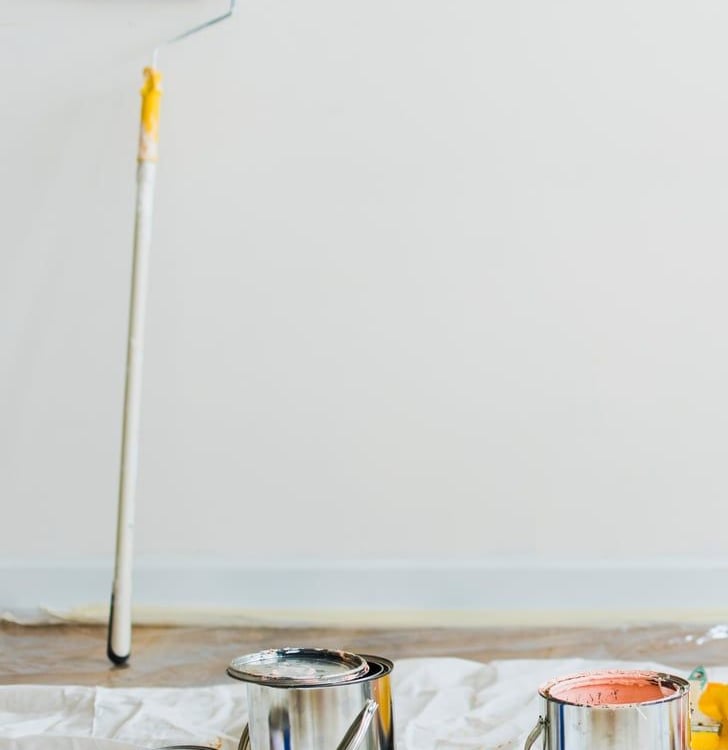 Pokój w trakcie malowania. Wałek oparty o ścianę na podłodze puszki farby rozłożone na folii malarskiej