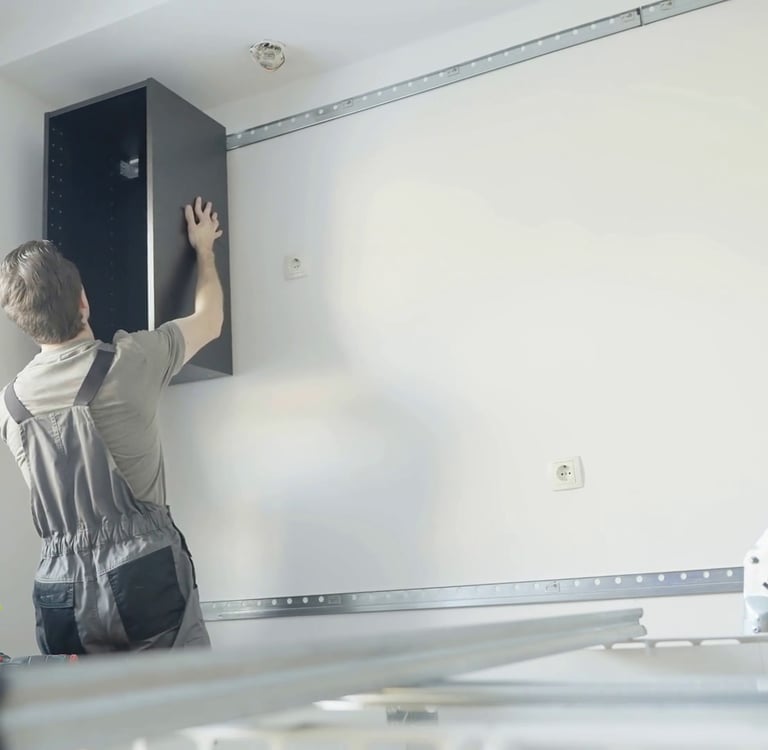 Mężczyzna montuje korpus szafki wiszącej za pomocą listwy montażowej 