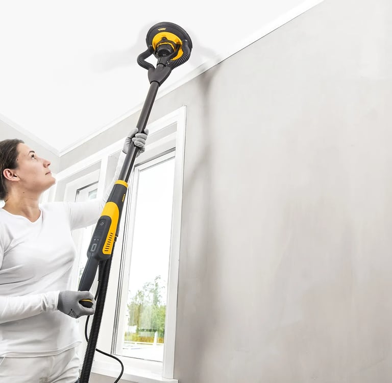 Kobieta szlifuje sufit za pomocą szlifierki tzw. Żyrafy