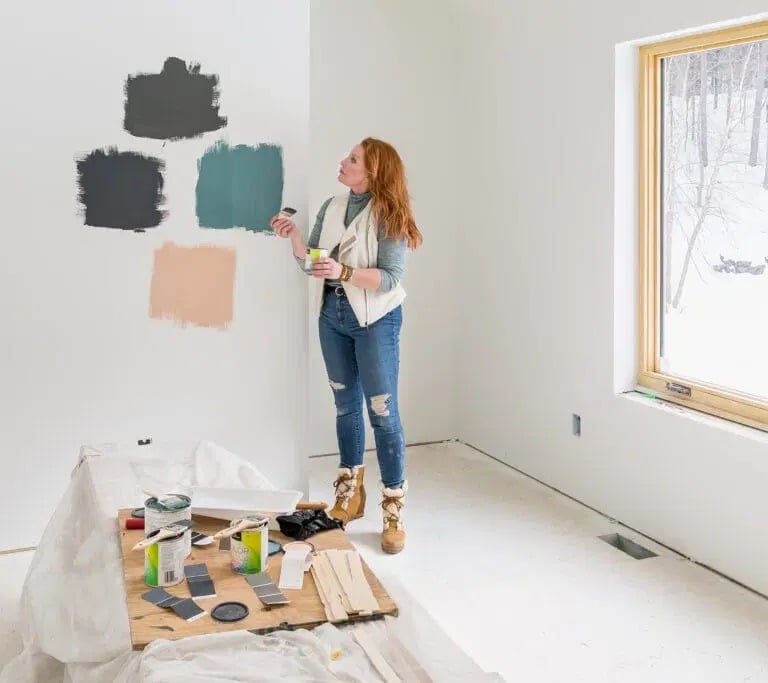 Kobieta stoi przed ścianą i porównuje próbki farb