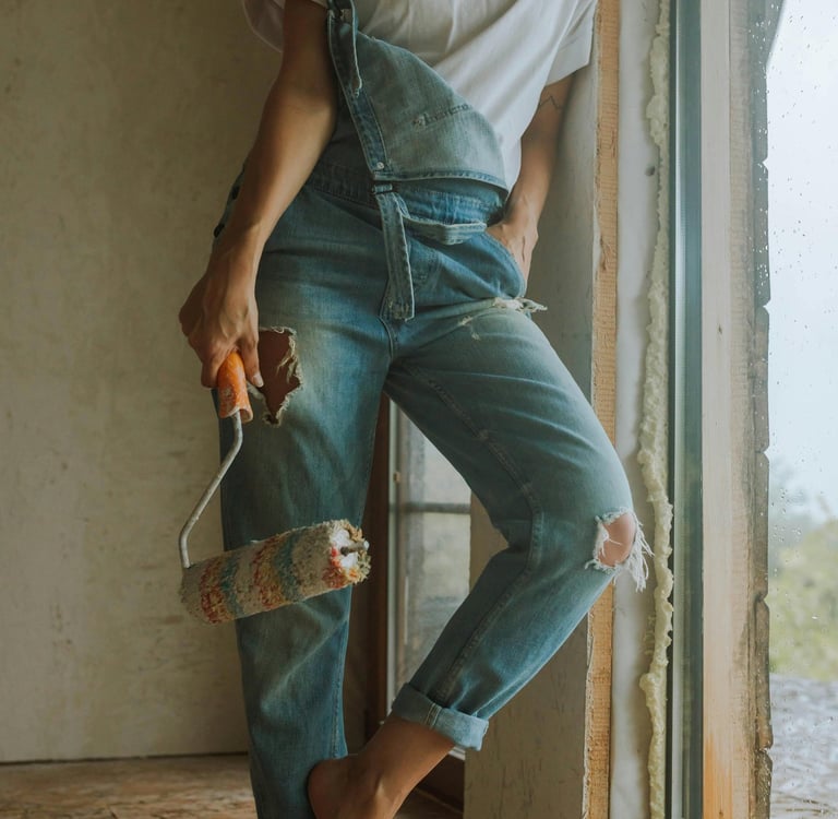 Kobieta w ubraniach roboczych trzyma wałek do malowania