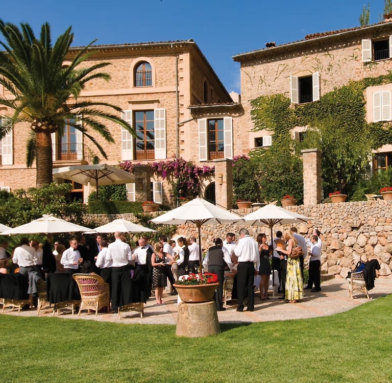 Luxury destination wedding reception at a historic stone villa in Mallorca with white umbrellas.