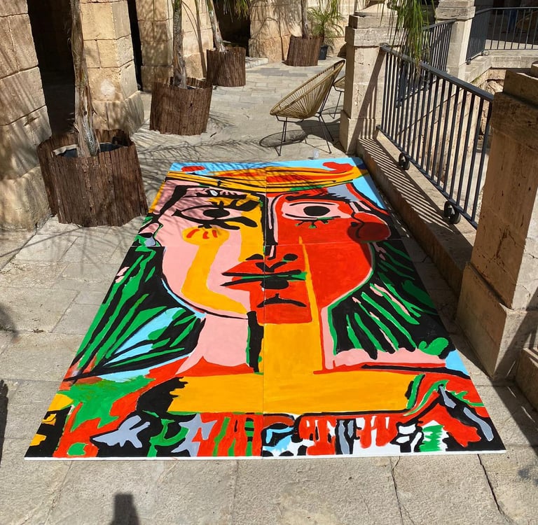 A vibrant cubist abstract portrait painting displayed on a stone patio in an outdoor courtyard.