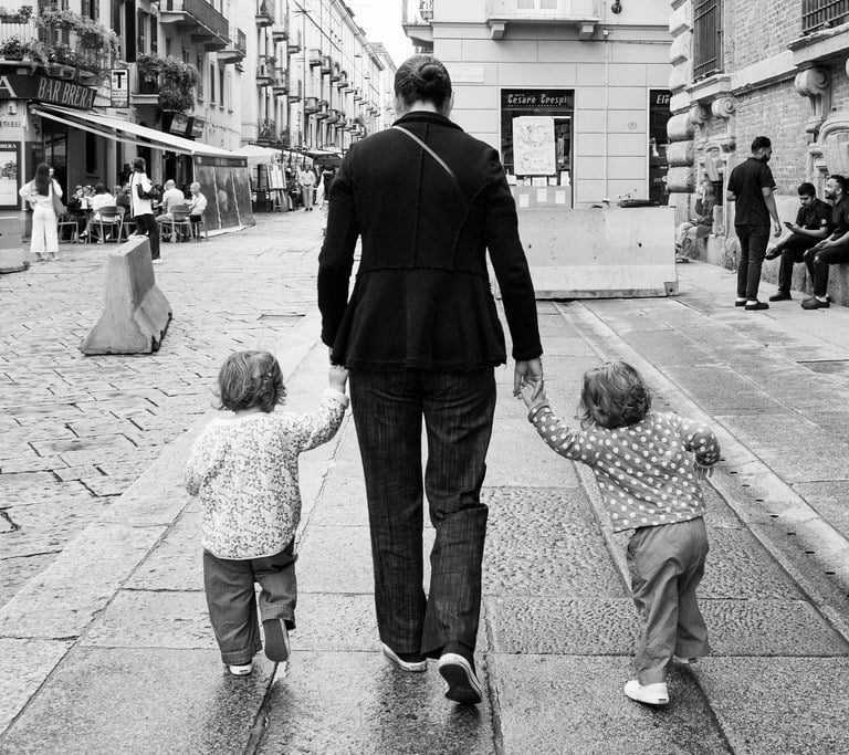Mother takes her two children by the hand as the walk along the street in Milan, Italy