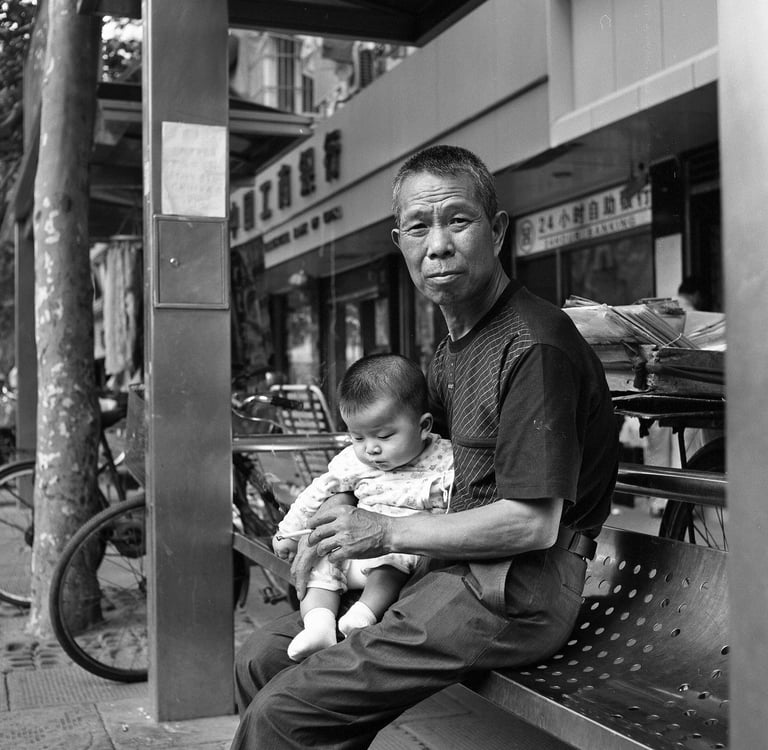 Man at bus stop holding grandchild and smoking a cigarette