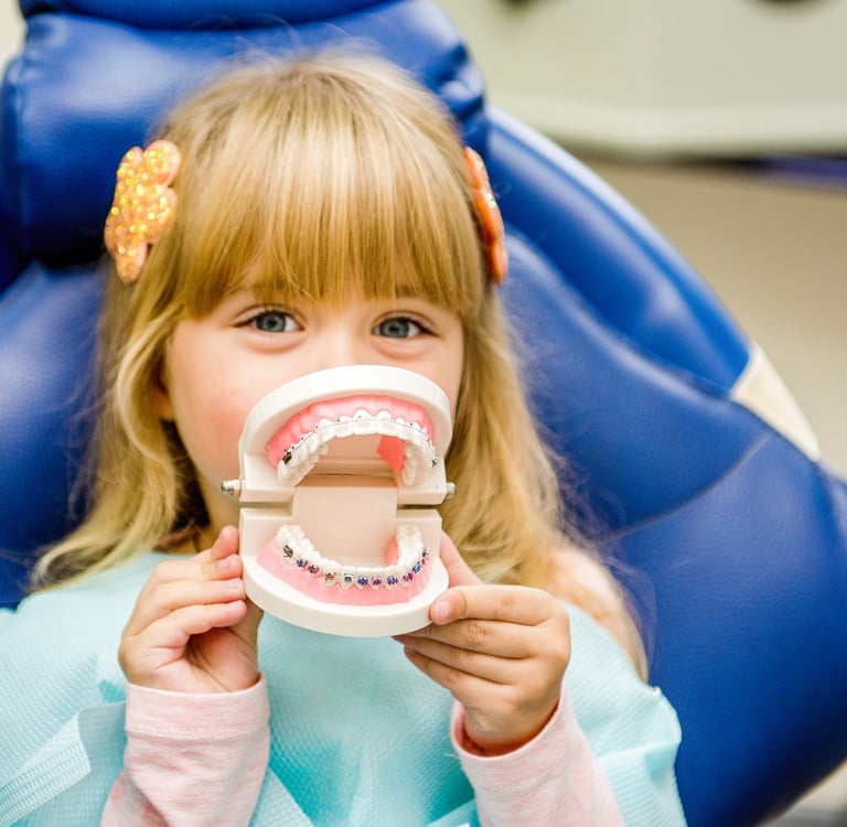 a little girl sitting in a chair with a toothbrush