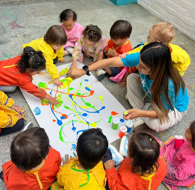 Niños con pinturas brillantes jugando sentados en el piso