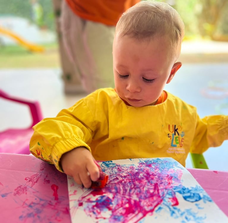 Niño pintando con crayolas en papel blanco