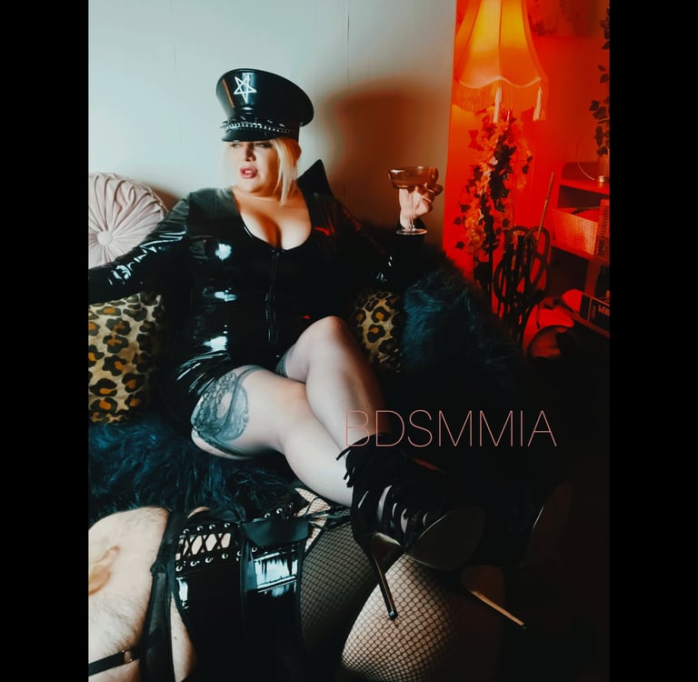 Leeds Dominatrix BDSMMIA reclines with her feet on a willing submisssive maid