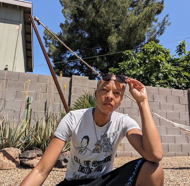 T. is a light skin Black person with a bald head n a desert background.