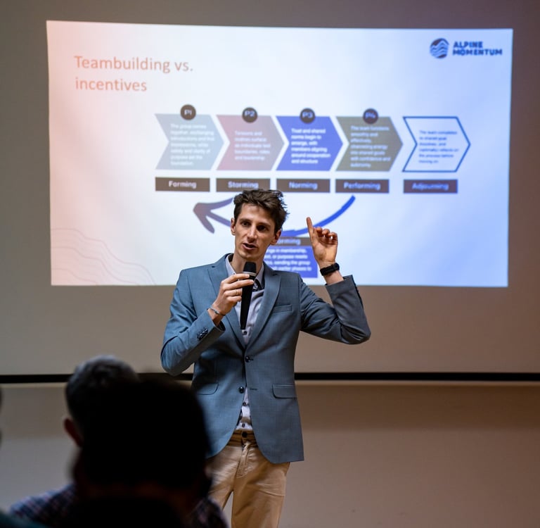 A male speaker presenting Tuckman's stages of team development at a corporate teambuilding workshop.