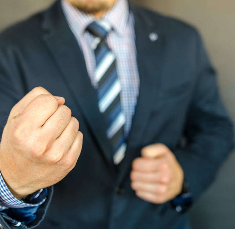A man in a suit clinching his fists.