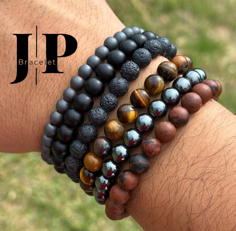Muñeca masculina con varias pulseras artesanales de piedras naturales en tonos negros, marrones 