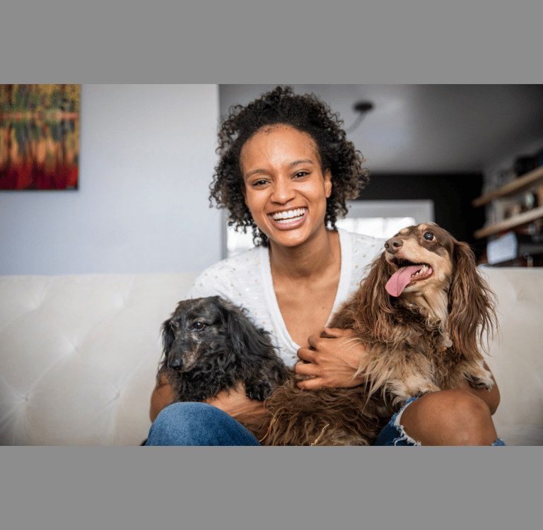 A beautiful young black woman holding her two elderly dogs