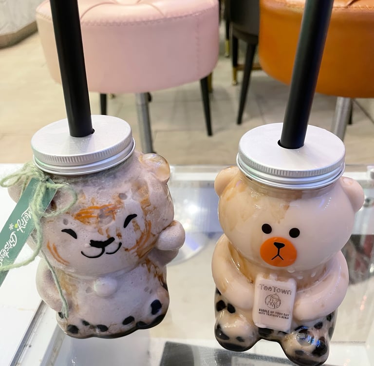 two cups of brown sugar milk tea with boba in animal-shaped cups on a table