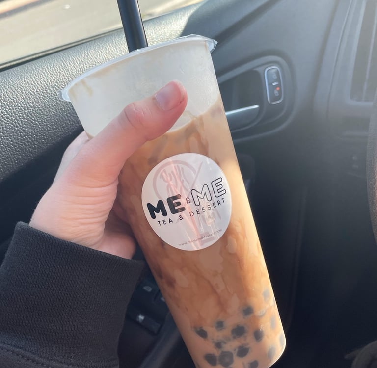 a person holding a cup of brown sugar milk tea with boba in a car