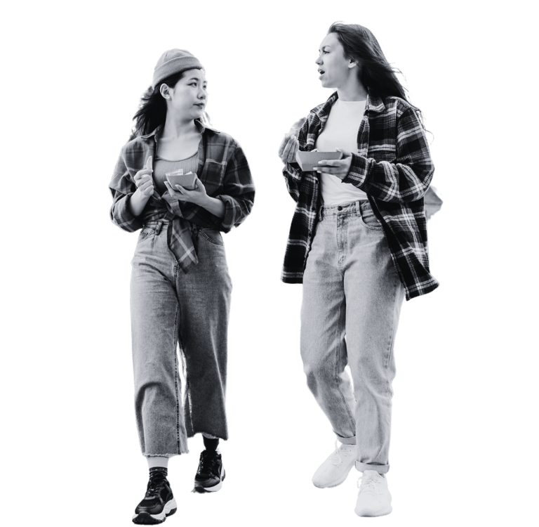 Two women walking with trays of food