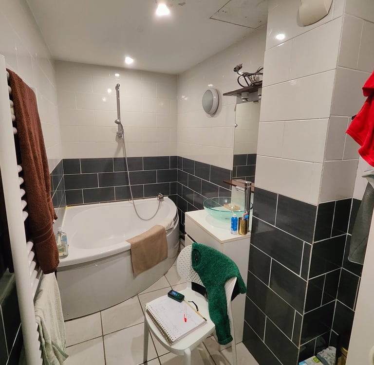 salle de bain avec baignoire d'angle et carrelage gris et blanc aux murs