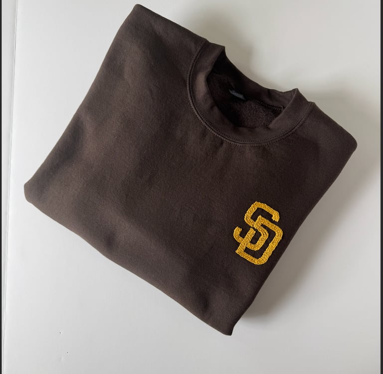 `a brown San Diego Padres sweatshirt with the SD logo embroidered in golden yellow