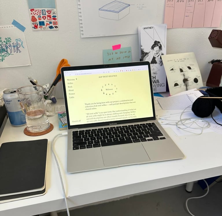 A pale yellow website beams from the screen of a laptop on a messy desk.